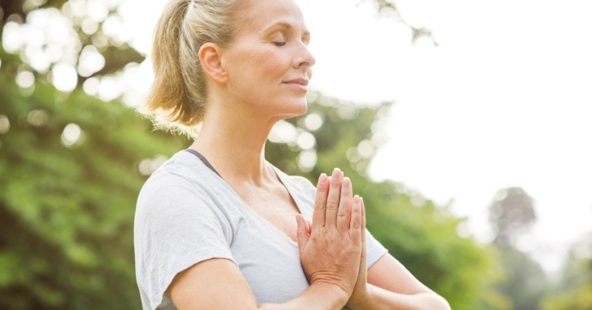 A retirement-aged woman mediates to feel calm.