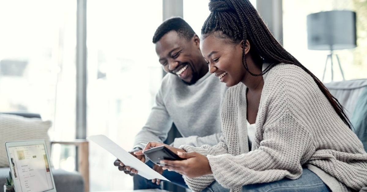 A young couple smile while looking at their financial documents