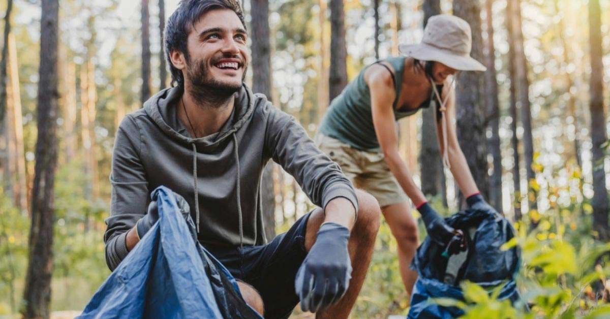 A man helps clean a forest of trash.