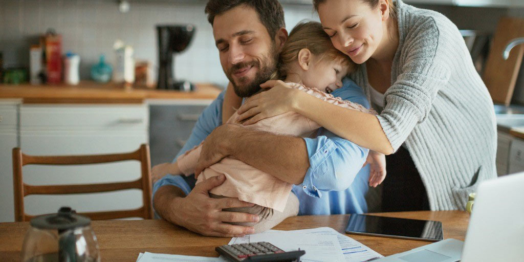 A young family embrace while researching life insurance options