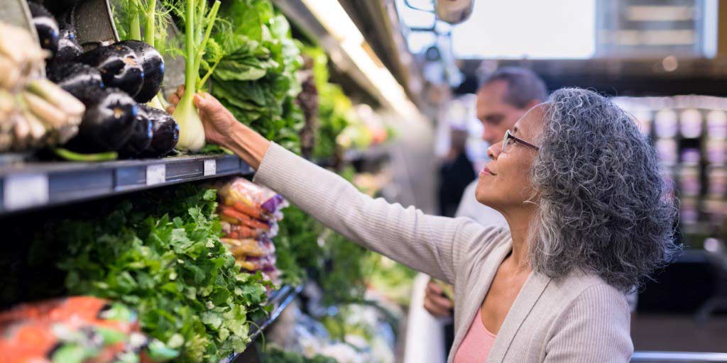 A retirement-aged woman shops for produce.