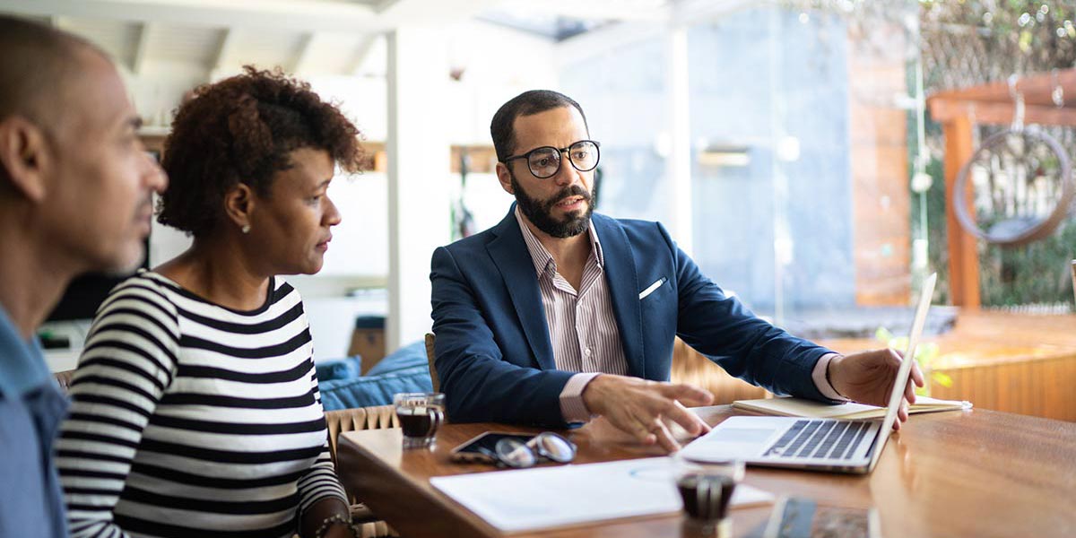 Three people meeting looking at a laptop