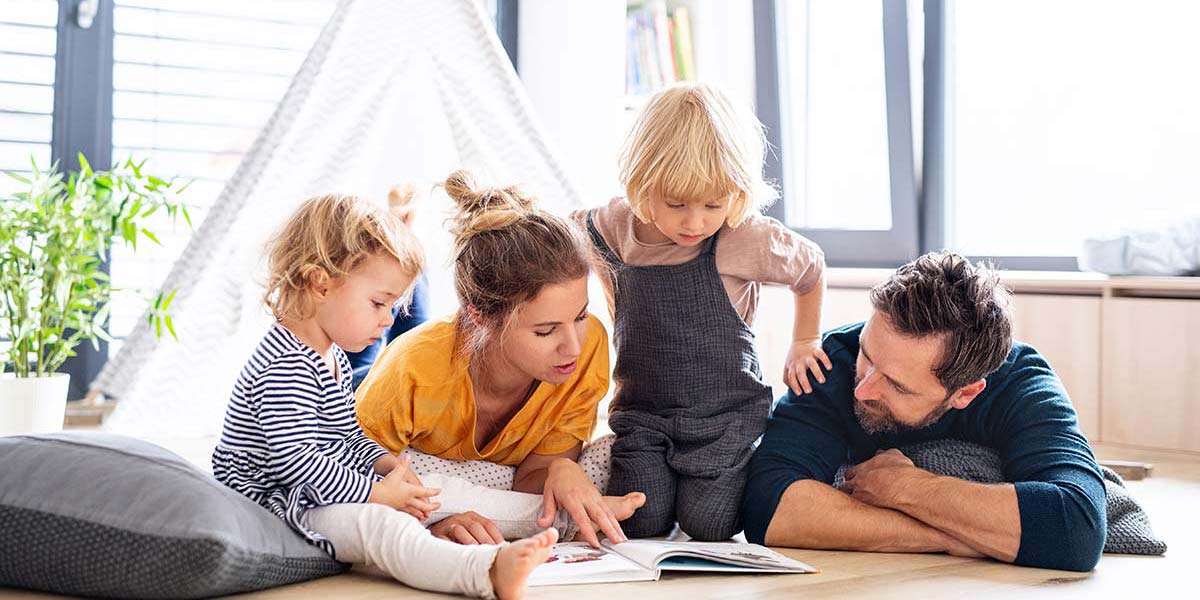 Family reading a book on the floor