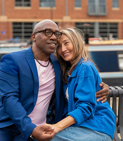 Man and a women sitting outside on riverwalk bench