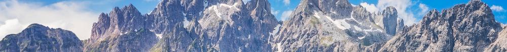An image of jagged and grass-covered mountains with bright blue sky.